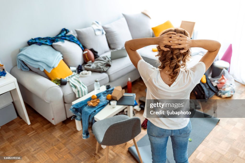 Housewife at modern home on sunny day looking at dirty room.