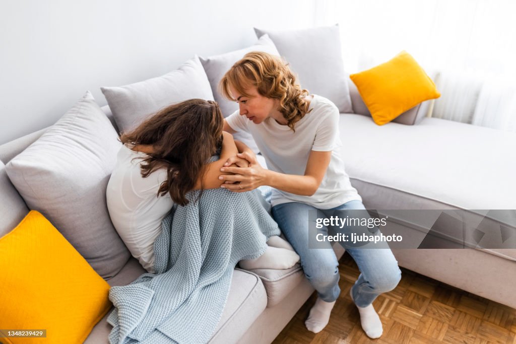Mature mother consoling her sad girl at home.