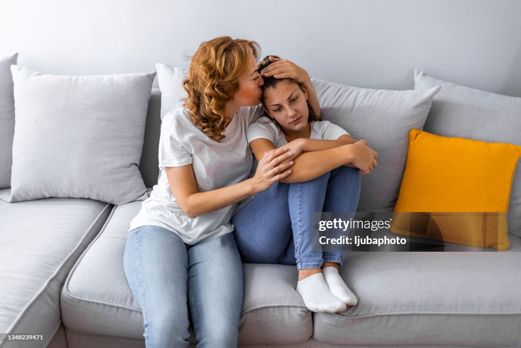 Mãe carinhosa acalmando e abraçando a filhazinha chateada
