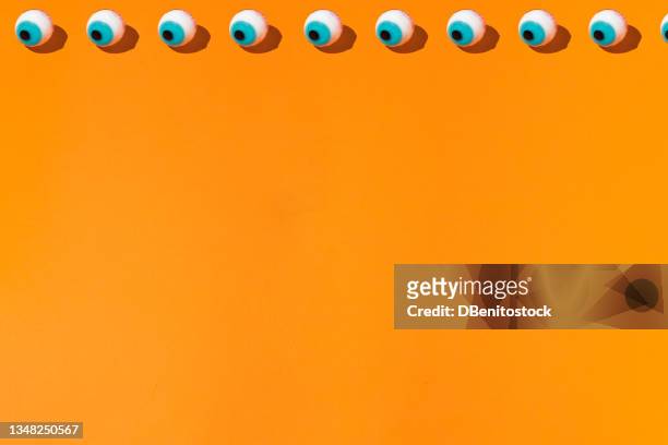 a top line of halloween candy ghoulish eyes pattern on a orange background. halloween and horror celebration concept. - naughty halloween stock pictures, royalty-free photos & images