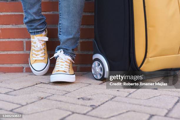 unrecognizable woman next to suitcase, against brick wall - koffer geht nicht zu stock-fotos und bilder