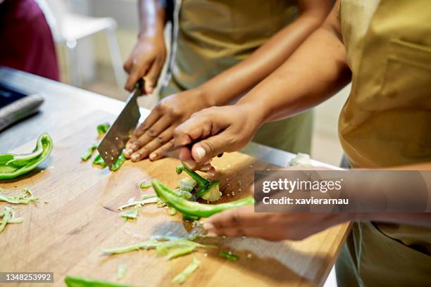 adult students slicing vegetable in cooking class - aula de culinária imagens e fotografias de stock