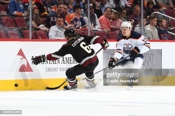 Jesse Puljujarvi of the Edmonton Oilers passes the puck past Jakob Chychrun of the Arizona Coyotes at Gila River Arena on October 21, 2021 in...