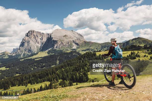 adventurous mountain biker enjoying the view of majestic mountains in dolomites - claus lange stock pictures, royalty-free photos & images