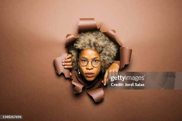 head of a woman coming out through a brown paper wall - dark panthera stockfoto's en -beelden