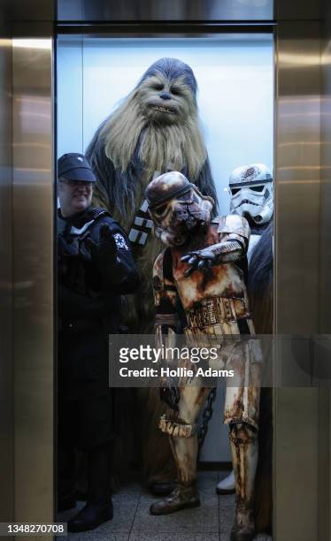 People dressed as Star Wars characters Chewbacca and some Stormtroopers pose in a lift as they attend MCM Comic Con London 2021 at ExCel on October...