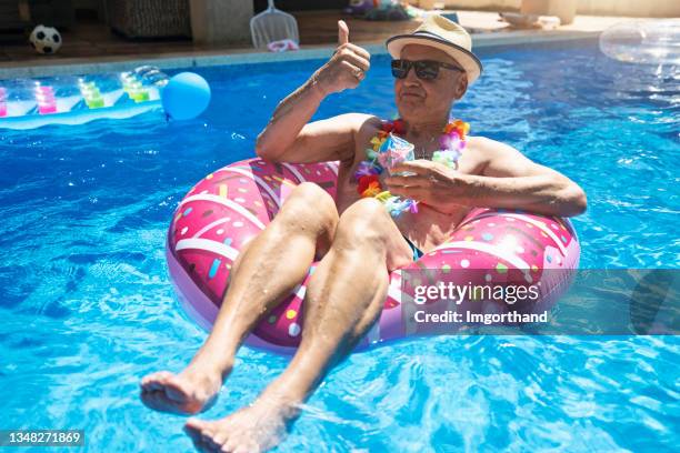 senior man enjoying relaxing in swimming pool - lazer imagens e fotografias de stock