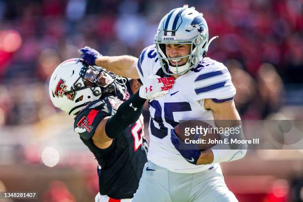 Receiver Kade Warner of the Kansas State Wildcats stiff arms defensive back Dadrion Taylor-Demerson of the Texas Tech Red Raiders during the second...