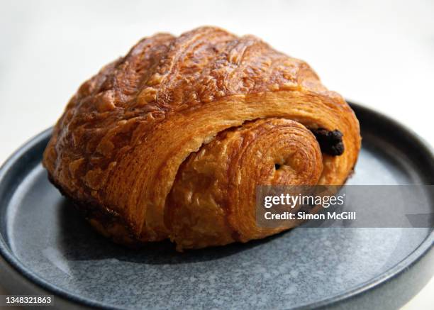 pain au chocolat on a blue gray plate on a white table - pain au chocolat stock-fotos und bilder