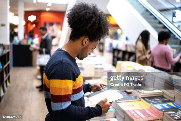 junger mann in einer buchhandlung im einkaufszentrum - bookshop stock-fotos und bilder