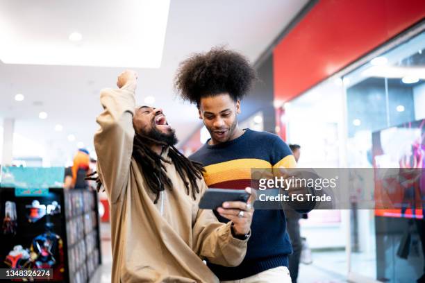 brothers watching sports or playing on the smartphone at the mall - match sport stock pictures, royalty-free photos & images