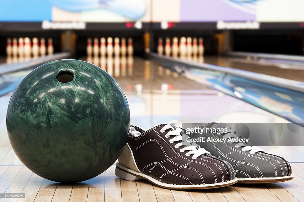 Bowling ball and shoes in bowling alley with background pins