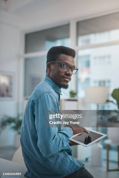 shot of a young businessman using a digital tablet in a modern office - jay space stock pictures, royalty-free photos & images