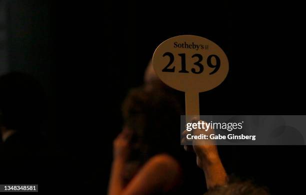 An attendee holds up a bid paddle to place a bid during the Sotheby's "Picasso: Masterworks From The MGM Resorts Fine Art Collection" auction at...