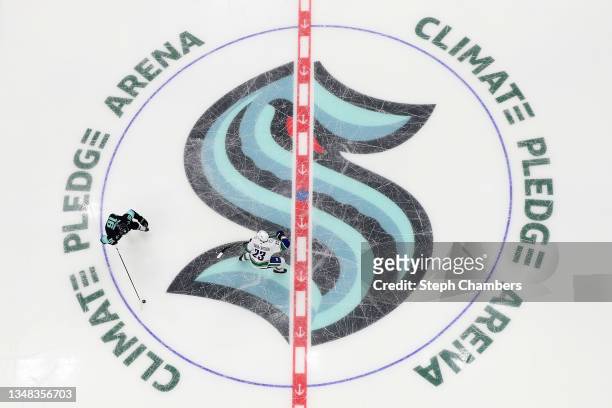 Jared McCann of the Seattle Kraken skates over the center ice logo while defended by Oliver Ekman-Larsson of the Vancouver Canucks during the...