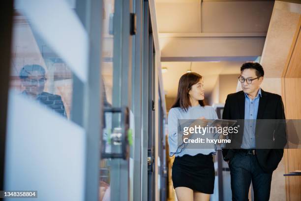 asian business people having discussion and walking through office corridor - asian ceo stock pictures, royalty-free photos & images