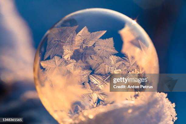 soap bubble in the snow in winter. ice patterns on the surface - frozen soap bubble stock pictures, royalty-free photos & images