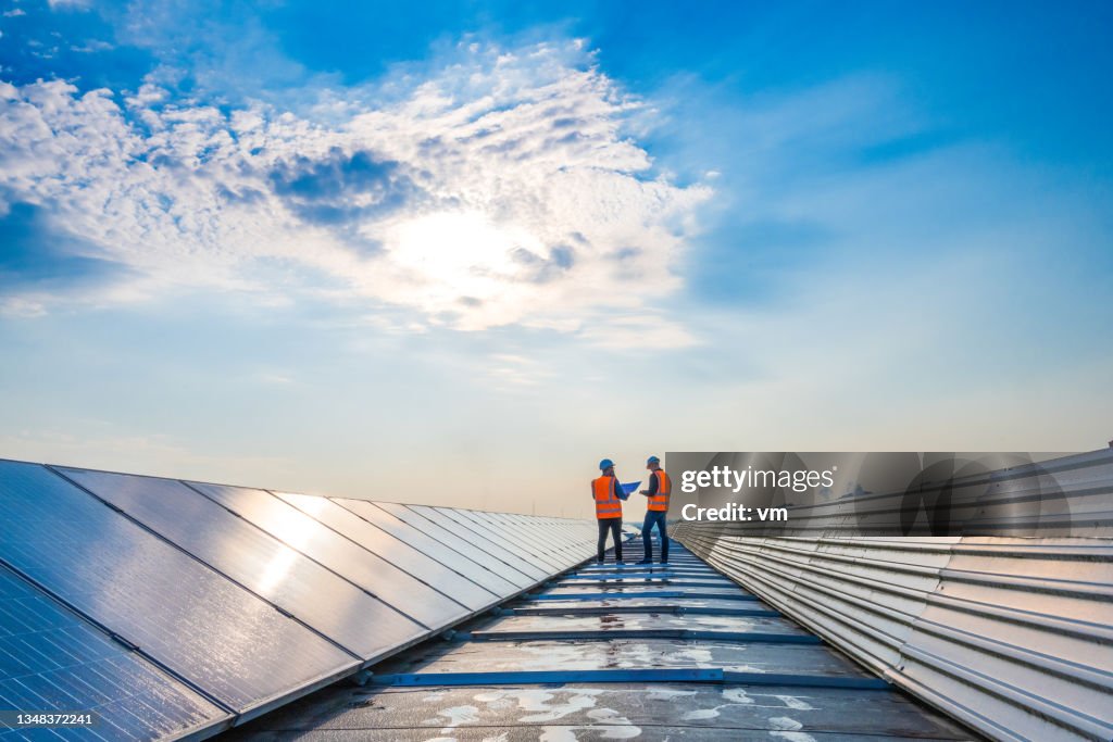 Deux techniciens à distance discutant entre de longues rangées de panneaux photovoltaïques