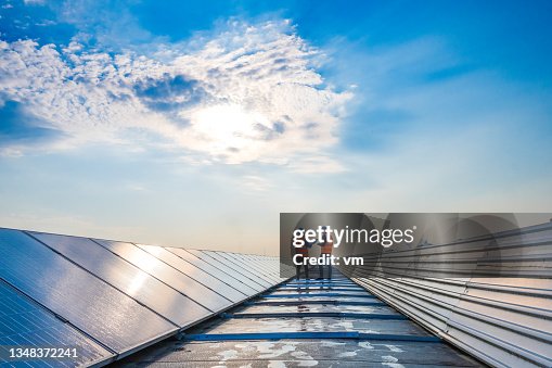 Two technicians in distance discussing between long rows of photovoltaic panels Two technicians in distance discussing between long rows of photovoltaic panels