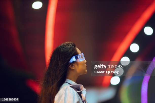 young asian woman standing under the illuminated pedestrian bridge at night looking into the distance - traffic management stock pictures, royalty-free photos & images