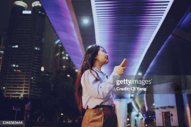 confident asian woman standing under a brightly lit pedestrian bridge - businesswoman under stock pictures, royalty-free photos & images