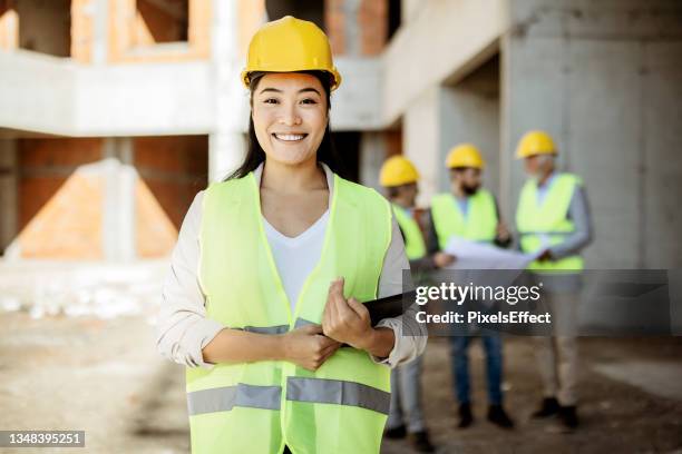 asian female architect at building site looking at camera - female builder stock pictures, royalty-free photos & images