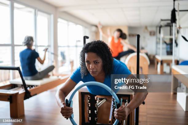 mature woman exercising with a pilates chair at a pilates studio - reformer stock pictures, royalty-free photos & images