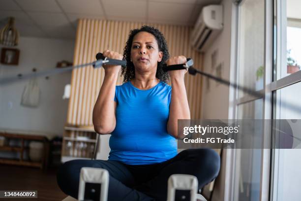 reife frau, die in einem pilates-studio trainiert - pilates gerät stock-fotos und bilder