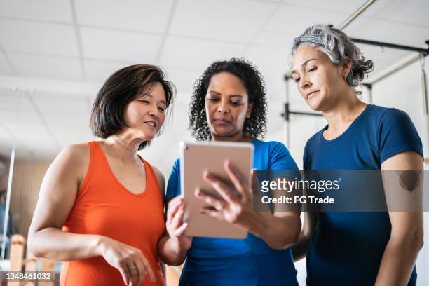 mature women looking at a digital tablet at a pilates studio - voice search stock pictures, royalty-free photos & images