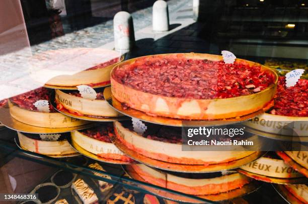 pink praline tarts stacked in a bakery window in lyon, france - praline stock pictures, royalty-free photos & images