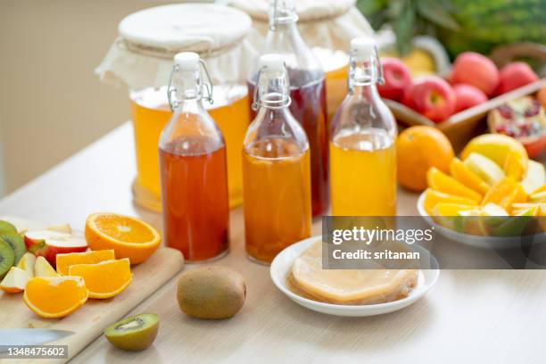 a scoby used for brewing kombucha is put on plate near bottle of various drink made from kombucha with many types of fruits - acetobacter bacteria stock-fotos und bilder