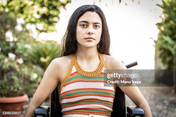 close up shot of depressed teenager sitting in wheelchair while looking at the camera. - mental disability stock pictures, royalty-free photos & images