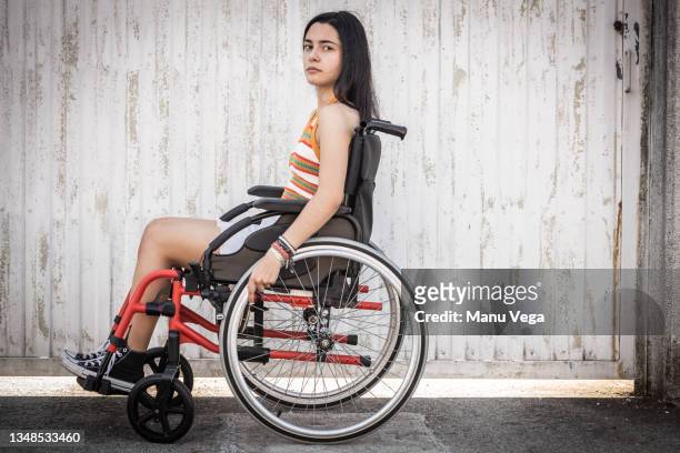 side view of young woman looking directly into camera with sad look. - woman wheelchair stock pictures, royalty-free photos & images