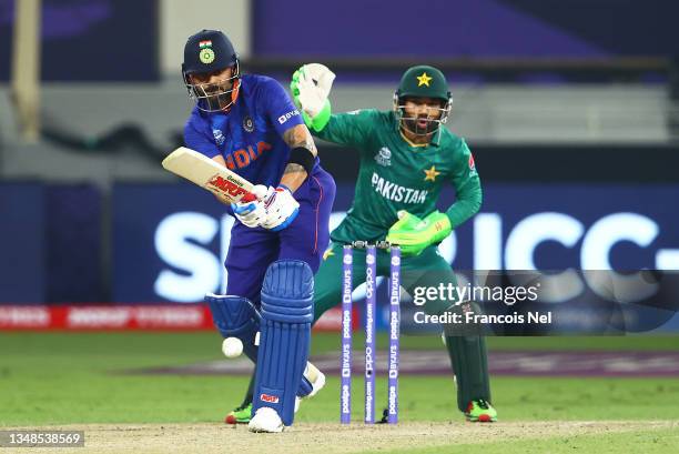 Virat Kohli of India plays a shot as Mohammad Rizwan of Pakistan looks on during the ICC Men's T20 World Cup match between India and Pakistan at...