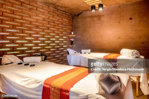 massage tables, with hot basalt lava stones used for lastone therapy, under dim lights and candles in a boutique spa hotel resort in tepoztlan, mexico - マッサージ台 ストックフォトと画像