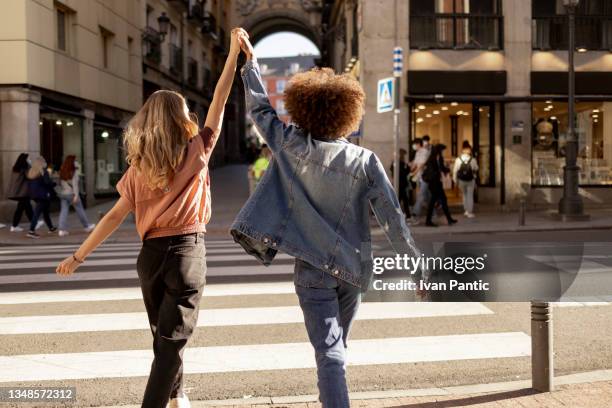 rear view of a happy diverse young lesbian couple having fun together in the city - direitos da mulher imagens e fotografias de stock