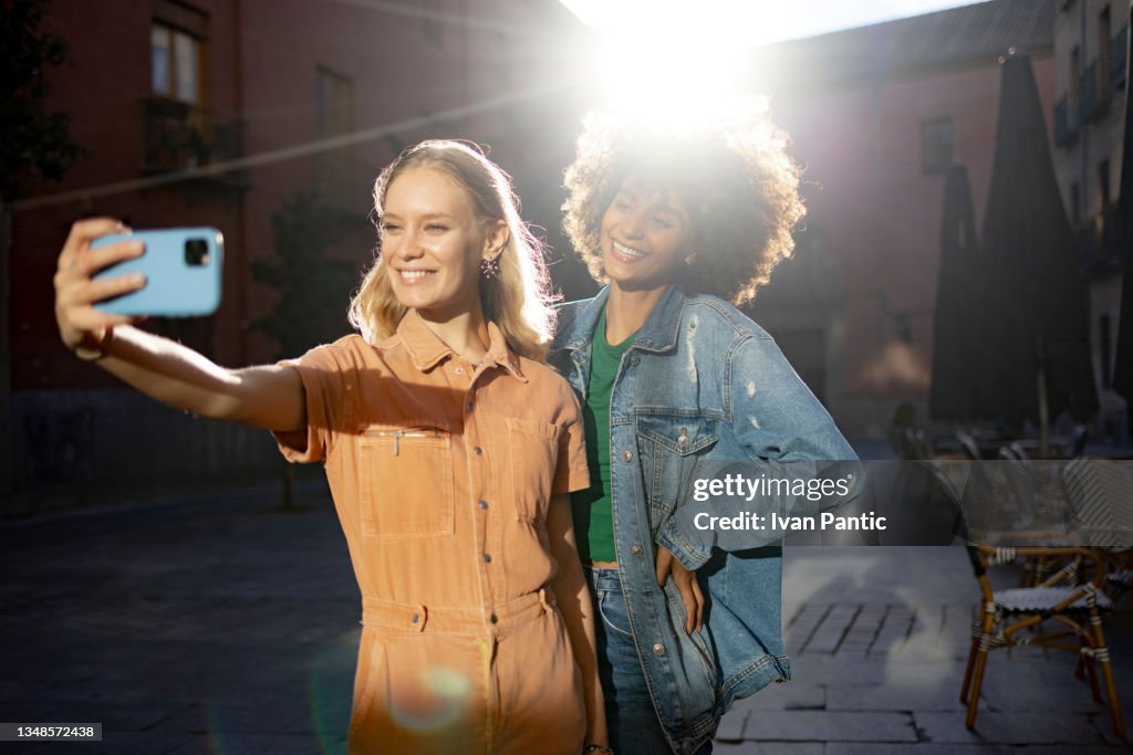 Young happy diverse female friends taking a selfie with a smart phone