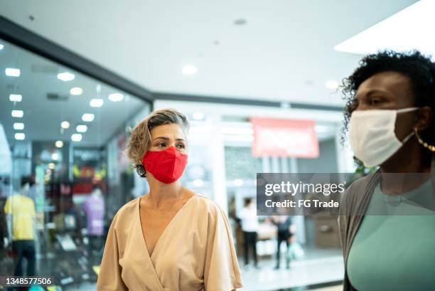 two female friends walking at the mall - using a face mask - shopping centre ad stock pictures, royalty-free photos & images