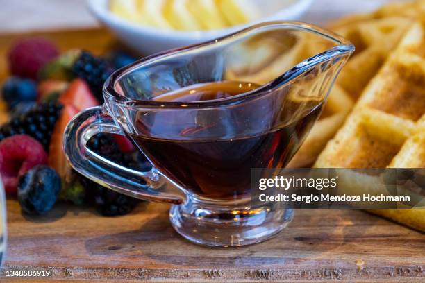 a small glass pitcher with maple syrup used for a delicious breakfast of belgian waffles, honey, fresh berries, butter - tepoztlan, mexico - raspberry syrup stock pictures, royalty-free photos & images