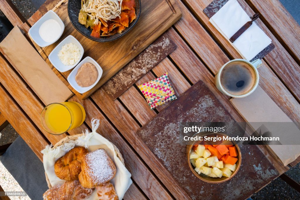 A delicious breakfast of Mexican chilaquiles, made of tortillas with shredded chicken and hot salsa sauce, and also fresh fruit, papaya and pineapple, Mexican food, top down view - Tepoztlan, Mexico