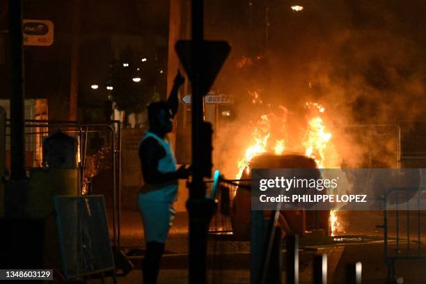 Man points at a burning car in Floirac on the outskirts of Bordeaux, south-western France on late June 29 during riots and incidents nationwide after...