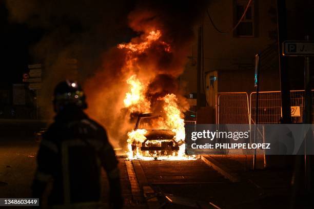 French firefighter looks at a burning car in Floirac on the outskirts of Bordeaux, south-western France on late June 29 during riots and incidents...