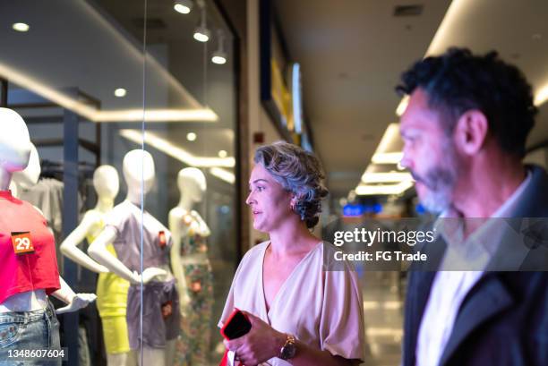 casal maduro olhando para uma vitrine no shopping - loja de roupas - fotografias e filmes do acervo