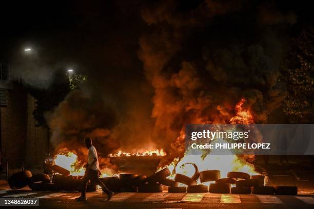 Man walks by burning tyres blocking a street in Bordeaux,, south-western France on late June 29 during riots and incidents nationwide after the...