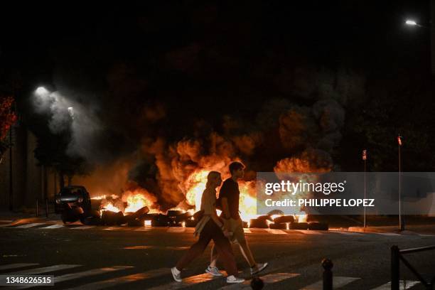 People walk by burning tyres blocking a street in Bordeaux,, south-western France on late June 29 during riots and incidents nationwide after the...