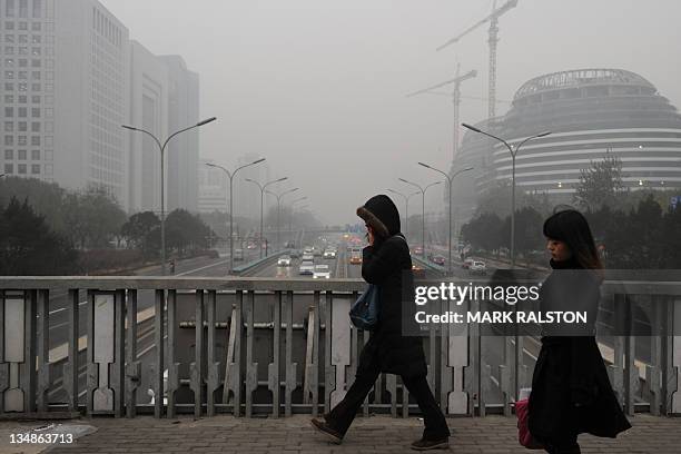 Pedestrians cross the second ring road as pollution reaches what the US Embassy monitoring station says are "Hazardous" levels in Beijing on December...