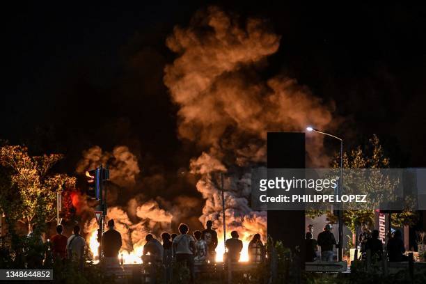 People look at burning tyres blocking a street in Bordeaux, south-western France on late June 29 during riots and incidents nationwide after the...