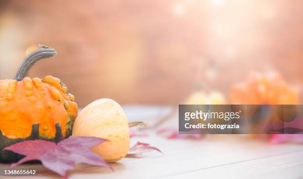 autumn decoration with pumpkins and leaves on wooden table against blurred background - harvest table stock-fotos und bilder