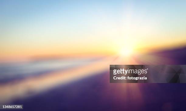 defocused sunset or sunrise at the beach - sunrise and sky fotografías e imágenes de stock