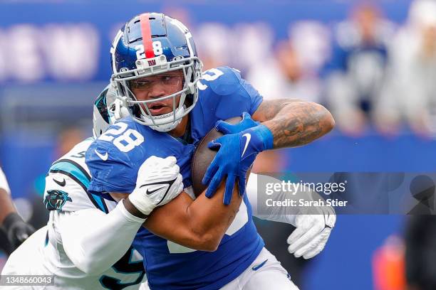 Devontae Booker of the New York Giants runs with the ball as Marquis Haynes of the Carolina Panthers defends during the first half in the game at...